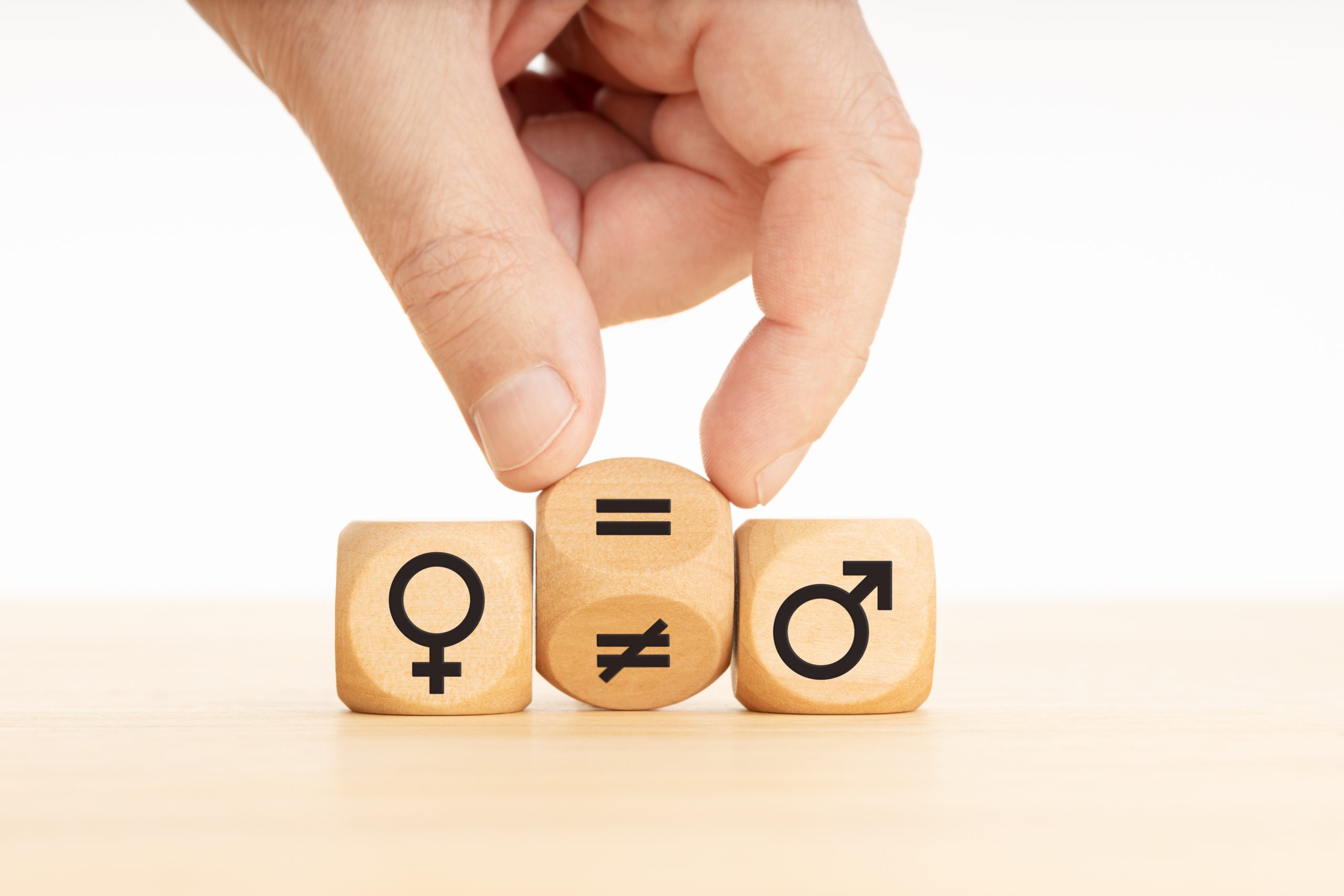 Gender equality concept. Hand turns a wooden block and changes a unequal sign to a equal sign between symbols of men and women