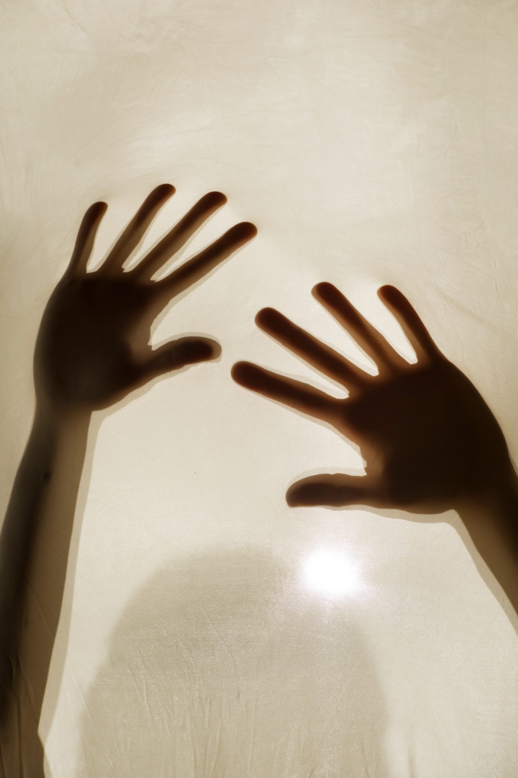 Photographic representation of violence on women, hands against sheet